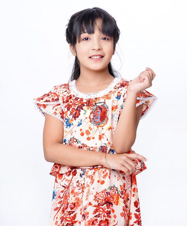 Peach A-line Frock in printed Georgette fabric. Designed with a round neck and tulip sleeves. Lace attachment at the neck, cuffs and princess lines. Detailed with extended waving ruffles around the waistline. Fancy button and slit at the front. Button opening at the back. Viscose lining in half-body.