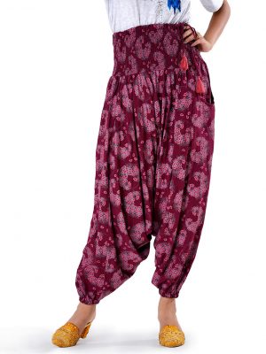 Burgundy all-over printed Harem pants in Viscose fabric. Designed with smoked waistline with adjustable tasseled waist cords and side packets.