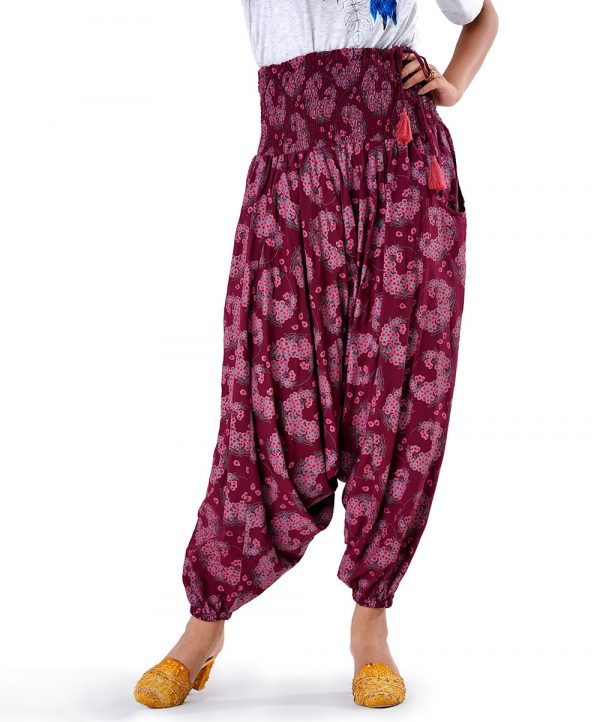 Burgundy all-over printed Harem pants in Viscose fabric. Designed with smoked waistline with adjustable tasseled waist cords and side packets.