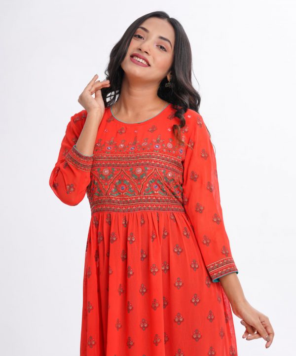 Orange all-over printed long Tunic in Georgette fabric. Designed with a round neck and three-quarter sleeves. Embellished with karchupi at the top front and gathers from the waistline.