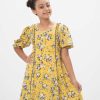 Yellow A-line frock in printed Georgette fabric. Features a round neck with buttons opening at the front and puff sleeves. Lace and frill detailing at the front. Viscose lining in full-body.