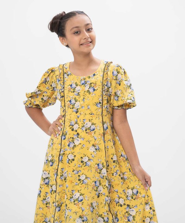 Yellow A-line frock in printed Georgette fabric. Features a round neck with buttons opening at the front and puff sleeves. Lace and frill detailing at the front. Viscose lining in full-body.