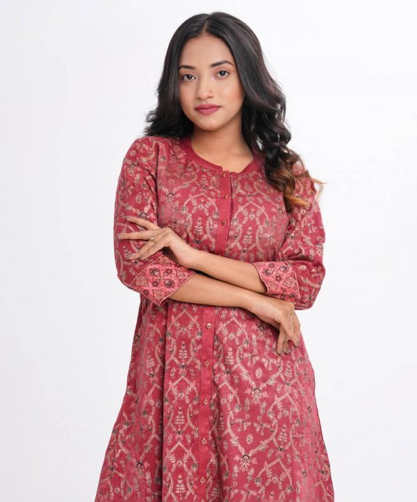 Garnet pink all-over printed A-line long Tunic in Velvet finish Georgette fabric. Features a low mock neck with a front button opening and three-quarter sleeves. Embellished with karchupi at the front and cuffs. Unlined.