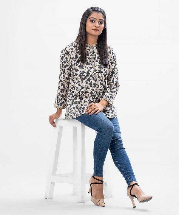 Off-white A-line Tunic in printed Georgette fabric. Features a band neck with button opening at the front and full sleeves. Designed with pin tucks at the front. Unlined.