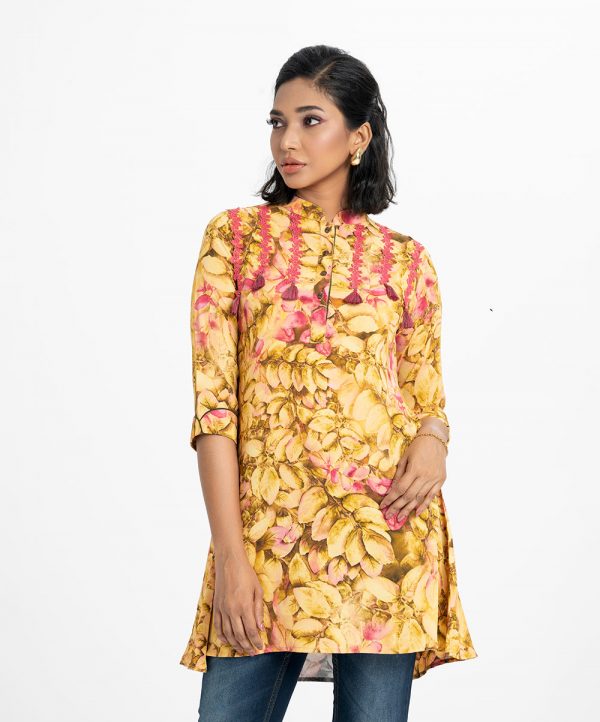 Ladies A-Line Shirt in printed georgette fabric. Stand collar, roll-up sleeved. Button fasting and attached lace and tassel tie at the front.
