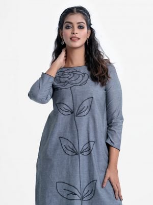 Women's high-low hem kameez in chambray fabric. Boat neck, full-sleeved. Big flower and leaf design embroidery at the front and backside. Inseam pockets.