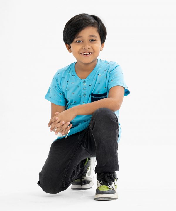 Kid boys henley T-shirt in cotton single jersey fabric. Rounded scoop neckline with front button fastening and short sleeves. All-over playfull prints with a chest pocket.
