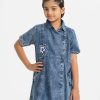 Kids girl A-line retro wrap style tunic in denim fabric. Classic collar, Short sleeved. Button fastening at the front. inseam pockets and attached patch at the front.