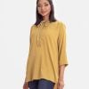 Ladies shirt in joom fabric. Round neck with tassel tie., long-sleeved with roll-up. High-low hem and button fastening at the front.