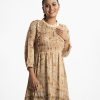 Women's frock style long tunic in floral printed zoom fabric. Mock neck, three-quarter sleeves. Frill trim with pin tuck at front. Gathered waistline with tie belt.