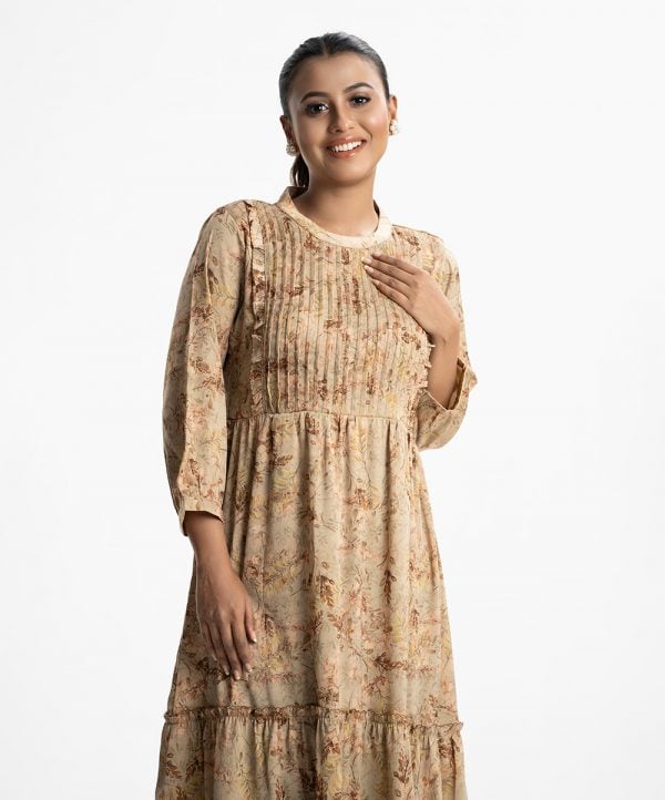 Women's frock style long tunic in floral printed zoom fabric. Mock neck, three-quarter sleeves. Frill trim with pin tuck at front. Gathered waistline with tie belt.