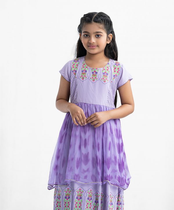 Kid girls printed frock in viscose fabric with chiffon fabric patch attached at waistline. Cap sleeves, round neck and tie-cord at back.