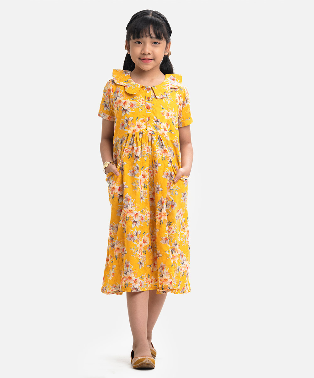 Kid girls frock in printed viscose fabric. Short sleeves, round neck with buttons placket. Two pockets at front and a tie-cord waist belt. Yellow Viscose A-line Frock