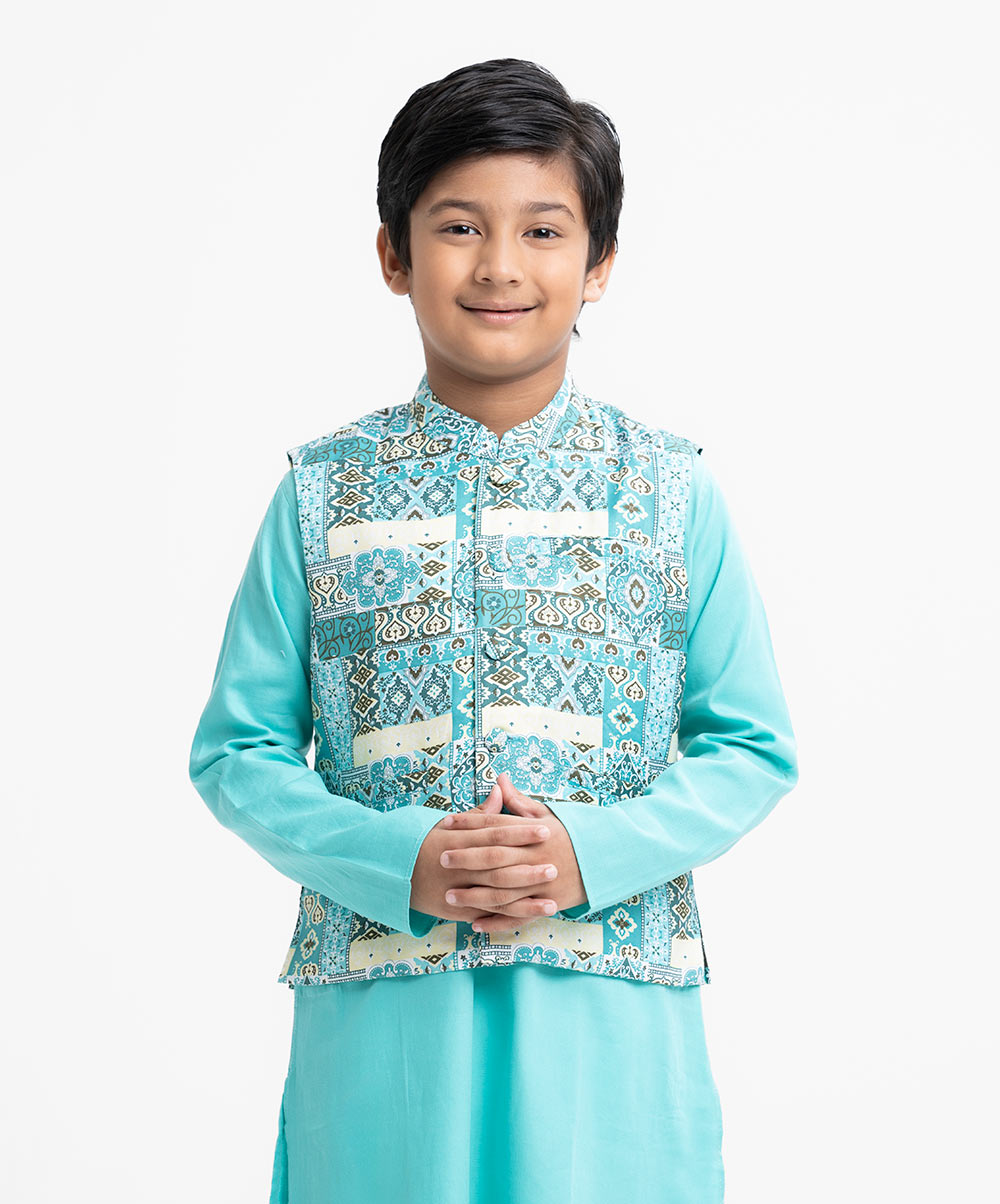 Kid boys' panjabi set in cotton-blended fabric. Mandarin collar, inseam pockets and long sleeves panjabi. Paired with a cotton-blended waistcoat and cotton pant. Teal Cotton Blended Panjabi Set