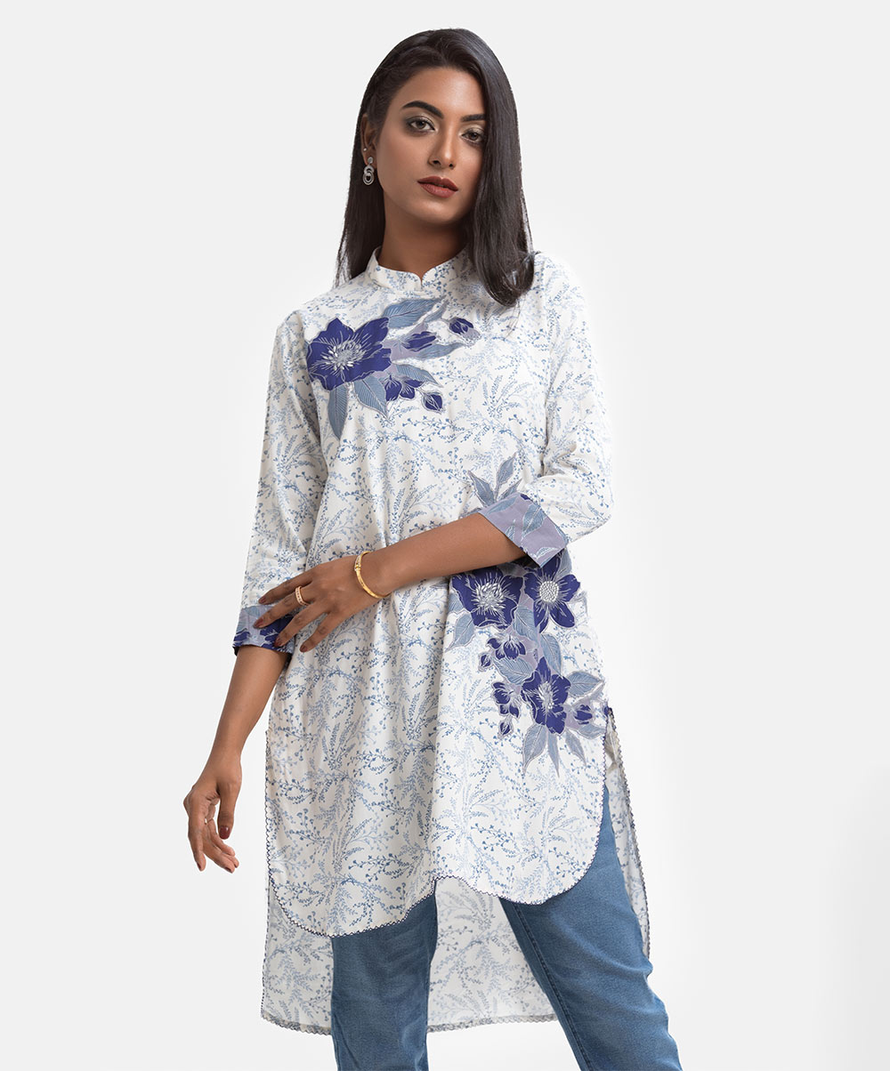 Women's high-low hem style tunic in printed viscose fabric. High neck, three-quarter sleeves. Embroidery at front & inseam side pockets. White Viscose High-low Hem Tunic